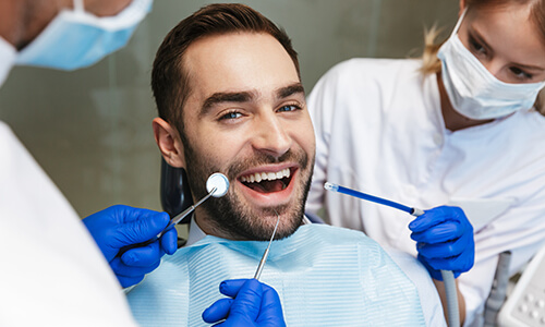 Dentists giving male patient a dental exam